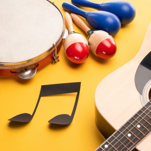 Musical instruments and paper cut music note on yellow background
